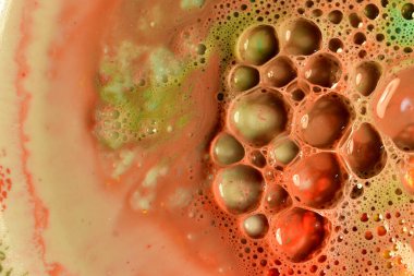 Açık kahverengi sıvı yüzey arka planında sabun köpüklerinin yakın plan görüntüsü.