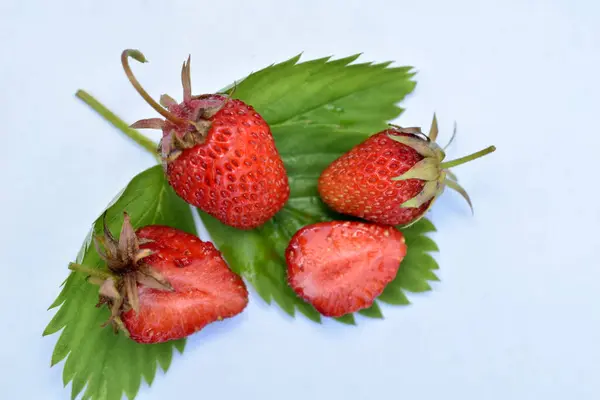 Reife Rote Beeren Ganz Und Erdbeerhälften Liegen Auf Grünen Blättern — Stockfoto