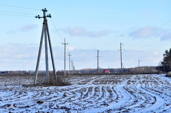 The picture shows a pole and a plowed field covered with snow.