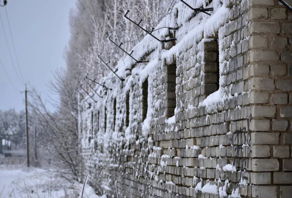 The picture shows a one-story stone building with square windows, the walls of which are covered with snow.