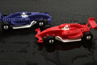 Children's toys, racing cars in blue and red on a dark road.