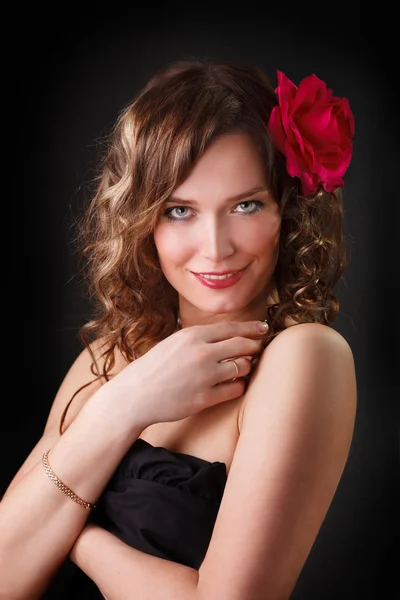 Porträtt av leende vacker ung kvinna med röd blomma Royaltyfria Stockbilder