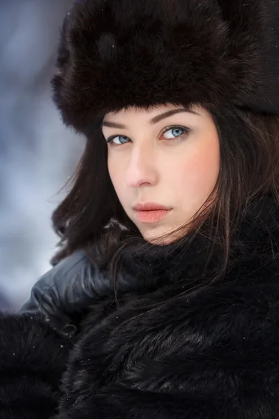 Young beautiful woman in fur hat in winter forest — Stock Photo, Image