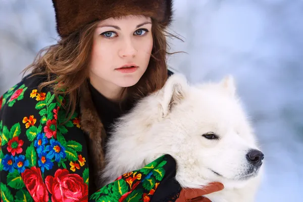Unga beaytiful kvinna i päls hattar i vinter skog med hund samo Stockfoto