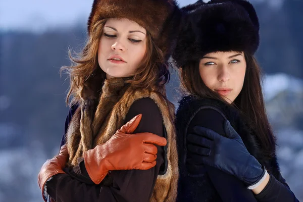 Två unga kvinna i päls hattar i vinter skog Royaltyfria Stockbilder