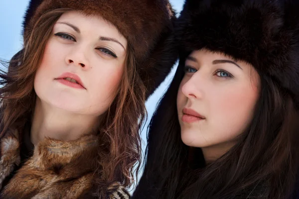 Twee jonge vrouw in bont hoeden in winter forest Stockfoto