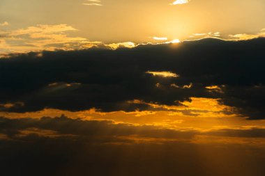 Güneşin ilahi ışığı. Güneşin bulutları ve ışınlarıyla dramatik akşam gökyüzü. Akşam gün batımında ya da sabah güneşinde güneş ışığı. Hareket halindeki bulutların panoramik görüntüsü. Güneşin ve bulutların altın ışınları.