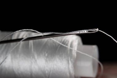 The thread is threaded through the eye of a sewing needle.Sewing and needlework classes.Workshop of hand craft and handmade.Workplace of the textile industry.The embroidery needle is stuck in a bobbin