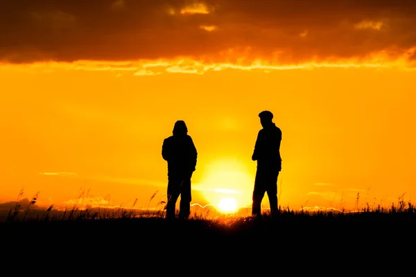 Két Sziluett Férfi Beszél Naplementekor Vagy Napkeltekor Drámai Égbolttal Felhőkkel Stock Kép