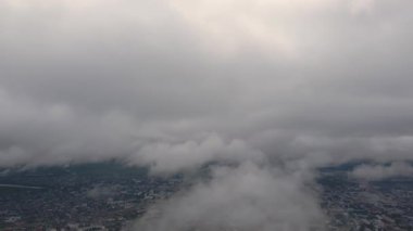 Yoğun bulutların arasında uçuyor. Gökyüzünde yağmur bulutları. Kümülüs bulutları, meteoroloji ve iklim çalışmaları. Bulutların yüksekliğinden şehrin videosu, hava fotoğrafı. Quadcopter, drone.