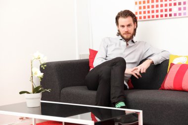 Adam kanepede oturuyor.