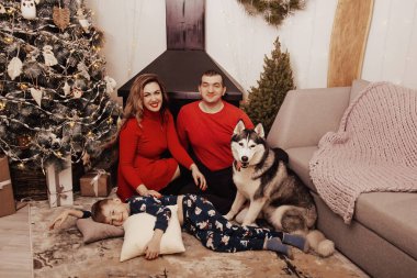 Anne, baba ve Noel ağacı arka plan üzerinde bir köpek Husky ile küçük çocuk