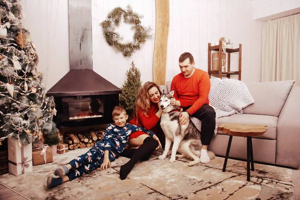 Anne, baba ve Noel ağacı arka plan üzerinde bir köpek Husky ile küçük çocuk