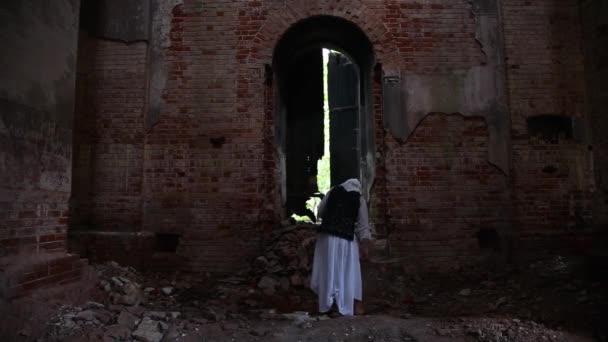 A creepy old woman witch or sorceress wanders through a ruined church — Stock Video