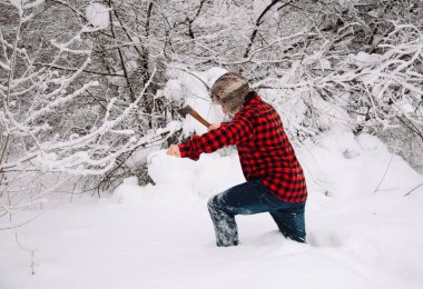 Kışın karlı ormanda oduncu. Baltalı hippi. Kışın açık havada ciddi bir oduncu. Oduncu yaşam tarzı. Ormanda çalışan yakışıklı adam..