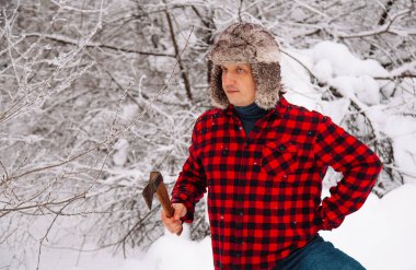 Kışın karlı ormanda oduncu. Baltalı hippi. Oduncu yaşam tarzı. Ormanda çalışan yakışıklı adam..