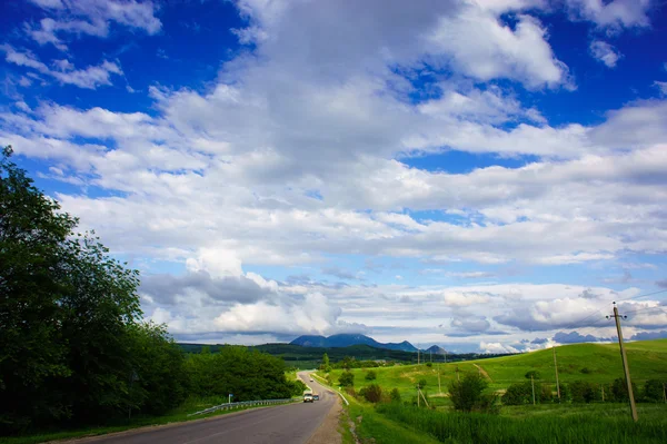 Carro em uma estrada vazia nas montanhas Imagens Royalty-Free