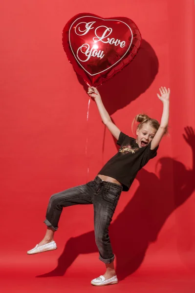 Meisje probeert te vliegen op de grote ballon op de rode achtergrond. — Stockfoto