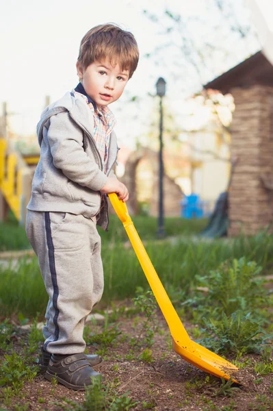 Garçon avec une pelle creuser dans le jardin . — Photo