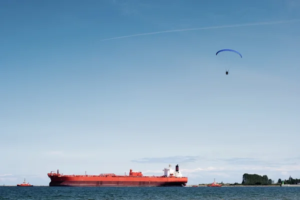 Schlepper helfen Frachter im Hafen zu verlassen und Drachenflieger. — Stockfoto