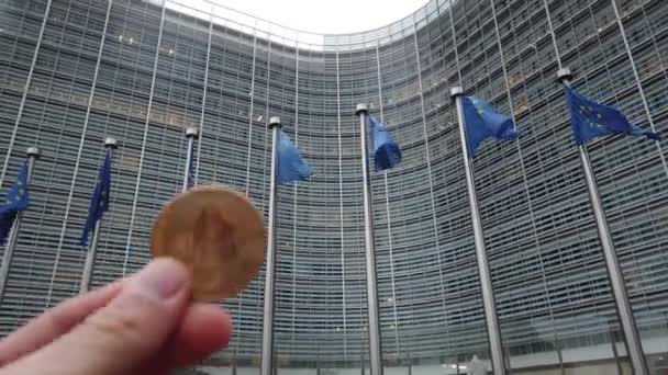 4K. Bitcoin przed flagami Unii Europejskiej machający na wietrze przed Komisją Europejską, budynek Berlaymont w centrum Brukseli, Belgia — Wideo stockowe