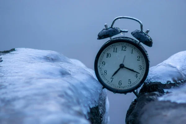 Frozen time. A clock frozen in ice. Extreme weather situation. Daylight saving time shift