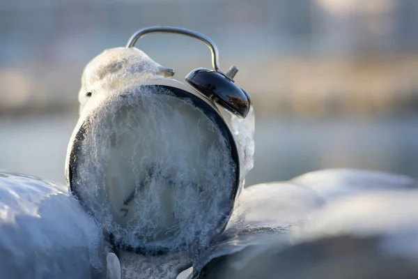 Frozen time. A clock frozen in ice. Extreme weather situation. Daylight saving time shift