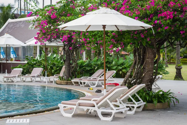 Couches with umbrellas around the pool — Stock Photo, Image