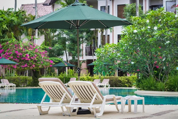 Couches with umbrellas around the pool — Stock Photo, Image