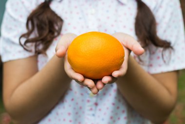 bir portakal tutan bir kız