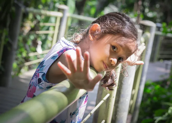 Gadis kecil yang manis meregangkan tangannya di pagar — Stok Foto