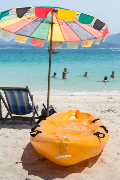 Barca in canoa sulla spiaggia con seggiolino e ombrellone — Foto Stock