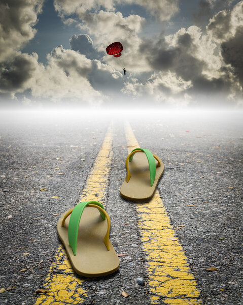 a pair of sandal on the road with parachute on the sky