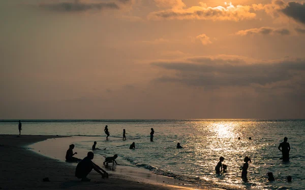 Silhouetted группа людей на пляже и в море — стоковое фото