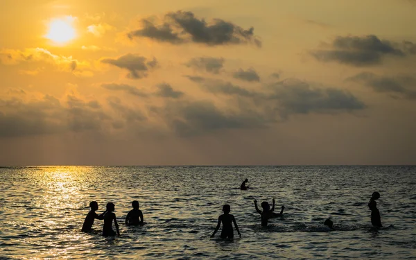 Silueta grupo de chicos están jugando una pelota en el mar —  Fotos de Stock