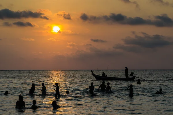 Silhouetted group of people are playing in the sea — Stock Photo, Image