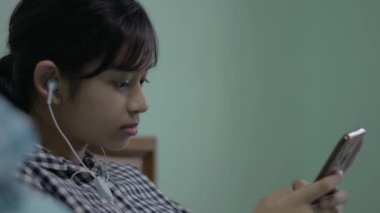 Taylandlı güzel bir kız yatakta yatarken akıllı telefonuyla arkadaşlarına mesaj yolluyor. Modern uzaklık iletişim teknolojisine sahip Asyalı genç kız..