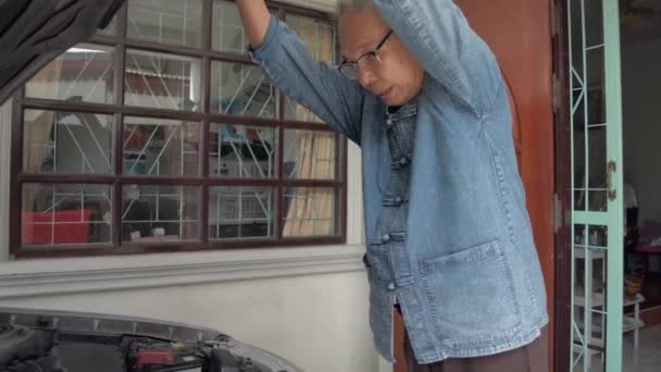 戴眼镜的亚洲老爷爷打开了他那辆老车的前盖 检查了家里发动机零部件的状况 老年人的退休生活 车辆维修 — 图库视频影像