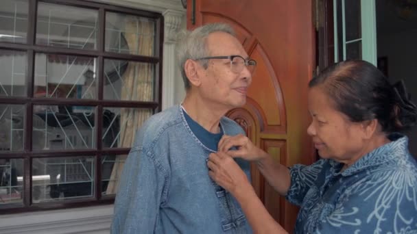 在离开家之前 亚洲的老祖母正在扣上衬衫 照顾她的丈夫 退休生活 结合在一起的家庭 老年夫妇生活方式 — 图库视频影像