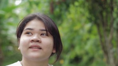 Portre mutlu Asyalı tombul yüzlü genç kız yaz boyunca doğal parka bakıyor. Şirin tombul bayan ergenler açık hava bahçesinde kalmaktan hoşlanırlar. Genç yaşam tarzı. Doğal koruma.