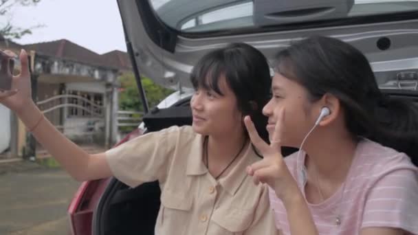 Taylandlı Genç Kız Kardeş Hatchback Vagonunun Arka Tarafında Otururken Cep — Stok video