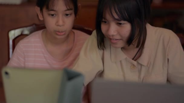 两个可爱的亚洲姐妹对一起使用数字设备感兴趣 可爱的少女坐在那里 享受在家庭隔离期间在数字平板电脑上观看社交视频的乐趣 年轻的生活方式 — 图库视频影像