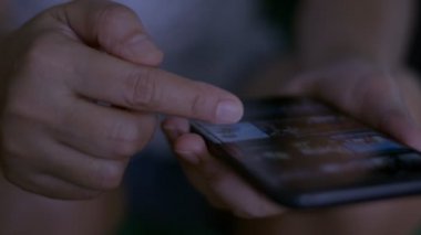Mobil akıllı telefondan dokunmatik ekran uygulaması kullanan kadının parmağını kapat. İnternetten film seçmek için internet kütüphanesinde film videosu taranıyor. Gezici eğlence.