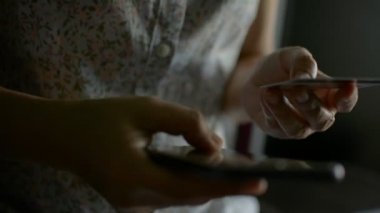 Kredi kartı tutan bir kadın cep telefonlu E-Bankacılık uygulama servisinden alışveriş yapıyor. Dijital cihazla kolay para kazanılır. İnternetten alışveriş. 