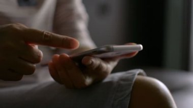 Ev kablosuz internetteki sosyal iletişim uygulamasında cep telefonunun dokunmatik ekranını kullanan sıradan giysili bir kadın. Dijital aygıtla ev izolasyonu.