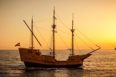 Medieval sailing ship in sunset clipart