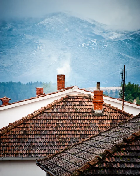 Střechy s kouřících komínů v zimě — Stock fotografie