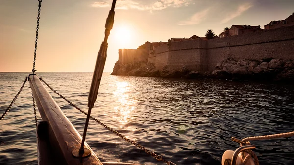 Old sailing ship sails into the sunset next to the city walls of — Stock Photo, Image