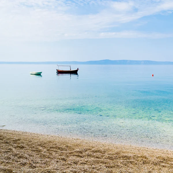 Två små båtar i lugna vatten nära den sandiga stranden — Stockfoto