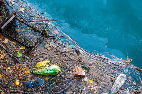 Загрязнение воды старый мусор и нефтяные пятна на поверхности реки

